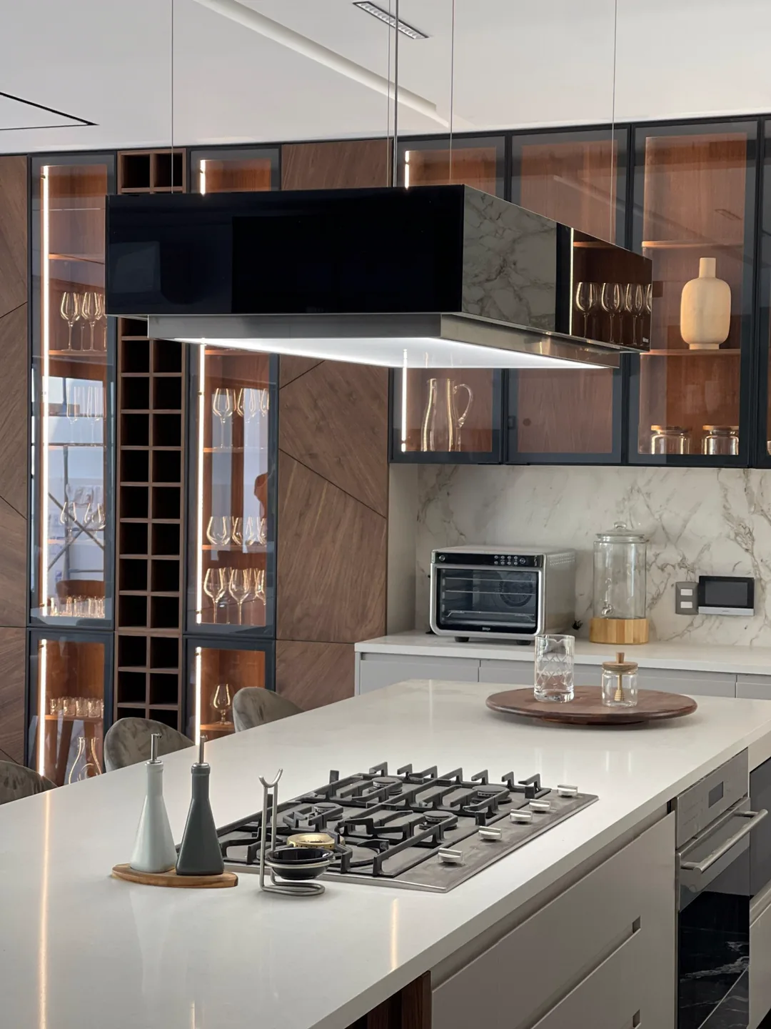 The kitchen photo uploaded to ReyAI — marble island with a gas hob, extractor hood and walnut cabinets.